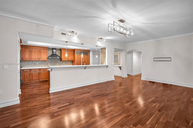 kitchen featuring hanging light fixtures, a breakfast bar area, wall chimney exhaust hood, and dark hardwood / wood-style flooring