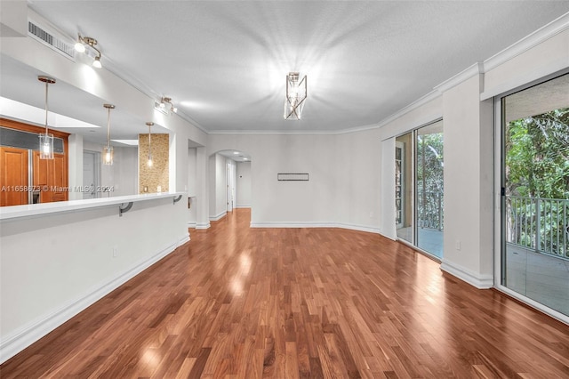 unfurnished living room featuring hardwood / wood-style flooring, a textured ceiling, and ornamental molding