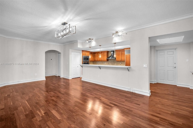 unfurnished living room featuring a skylight, hardwood / wood-style flooring, crown molding, and a textured ceiling