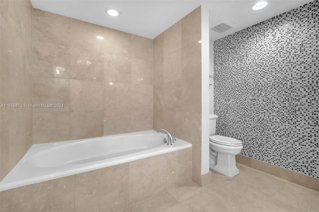 bathroom with tile walls, tile patterned flooring, toilet, and a relaxing tiled tub