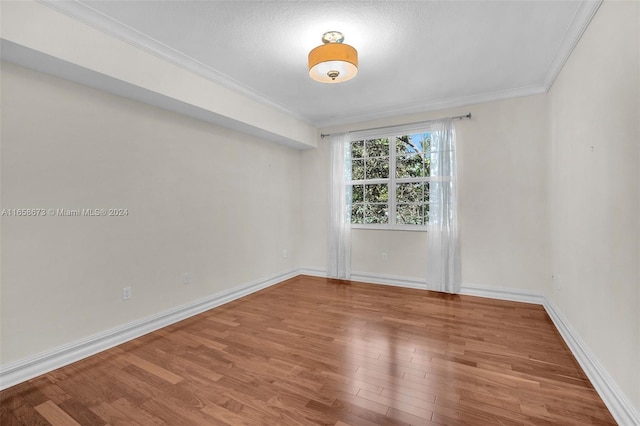 spare room featuring wood-type flooring and crown molding