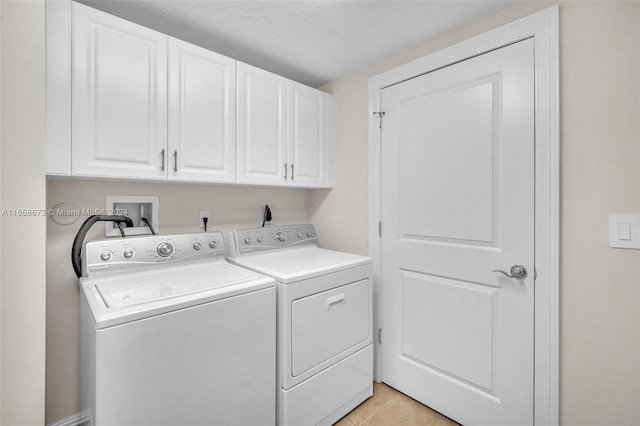 laundry area with cabinets, washer and dryer, and light tile patterned flooring