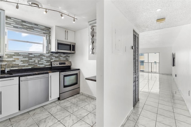 kitchen featuring white cabinets, sink, decorative backsplash, a textured ceiling, and appliances with stainless steel finishes