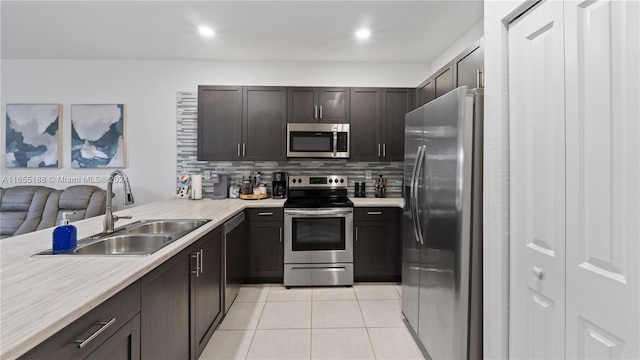 kitchen featuring tasteful backsplash, kitchen peninsula, light tile patterned floors, stainless steel appliances, and sink