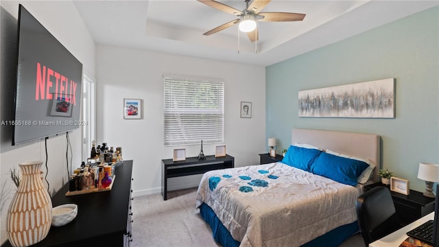 carpeted bedroom featuring ceiling fan and a raised ceiling