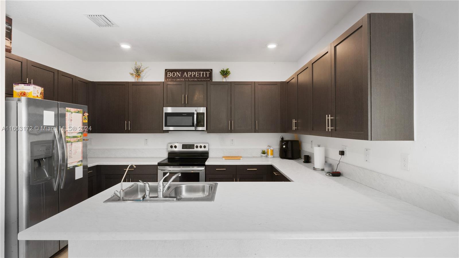 kitchen with dark brown cabinets, stainless steel appliances, sink, and kitchen peninsula