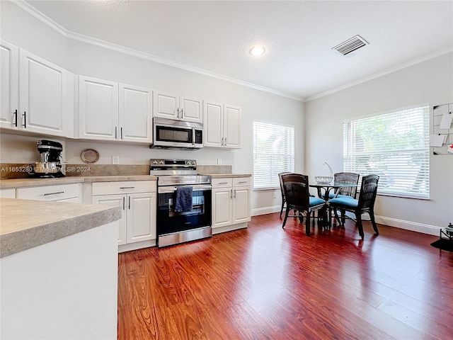 kitchen featuring white cabinetry, appliances with stainless steel finishes, dark hardwood / wood-style flooring, and ornamental molding