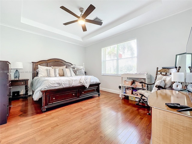 bedroom featuring ceiling fan, a raised ceiling, and light hardwood / wood-style flooring