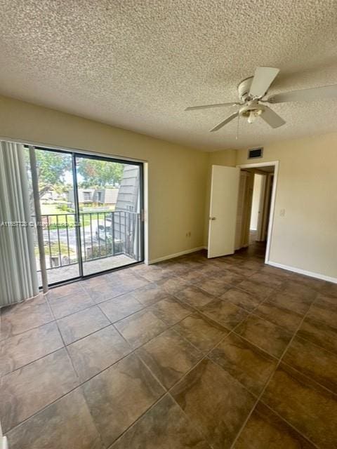 tiled empty room featuring ceiling fan and a textured ceiling