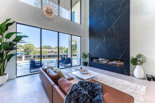 living room with a wealth of natural light, a premium fireplace, a notable chandelier, and a towering ceiling