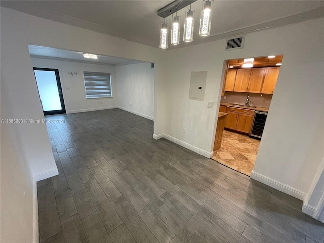 spare room with electric panel, wine cooler, sink, and dark hardwood / wood-style floors