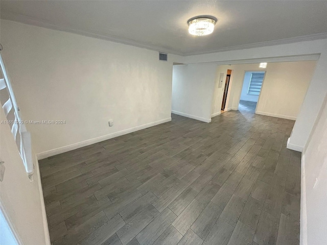 empty room featuring ornamental molding and dark wood-type flooring