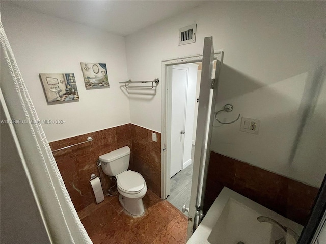 bathroom featuring tile walls, toilet, and sink