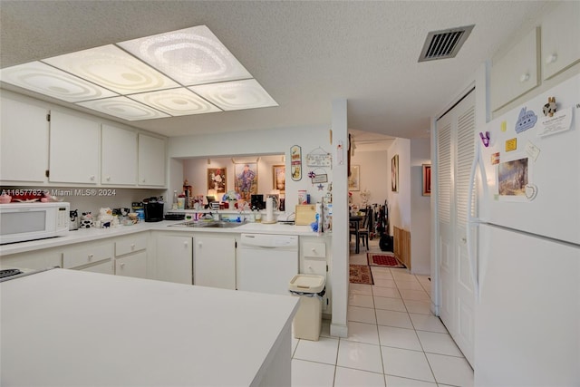 kitchen featuring white cabinets, sink, light tile patterned floors, white appliances, and a textured ceiling