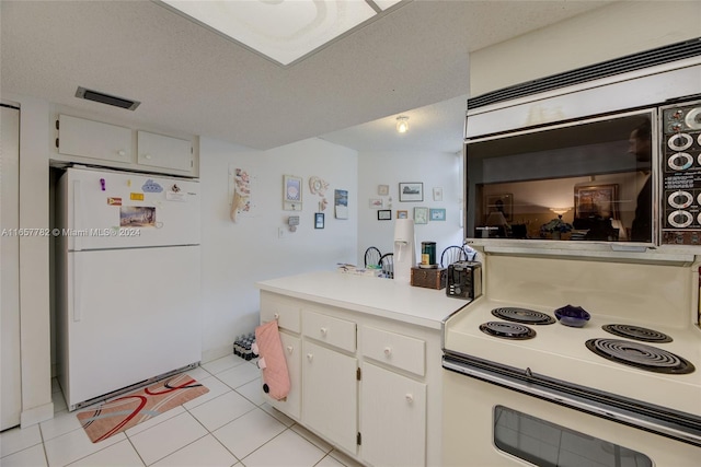 kitchen featuring white appliances, a textured ceiling, white cabinetry, and light tile patterned flooring