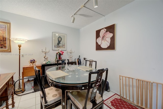 tiled dining room featuring a textured ceiling and track lighting