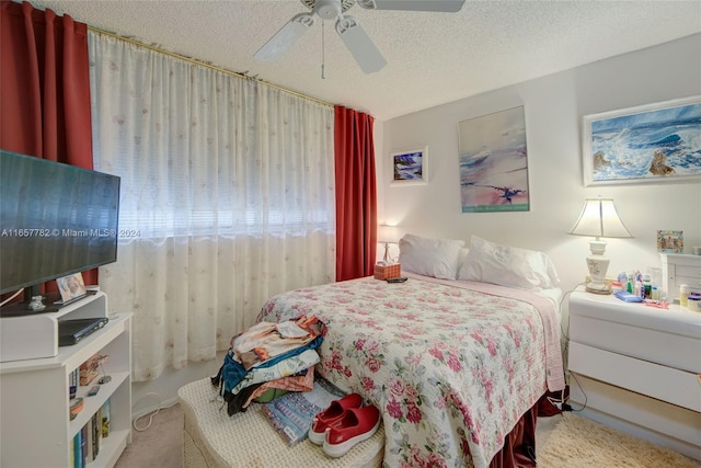 carpeted bedroom with ceiling fan and a textured ceiling