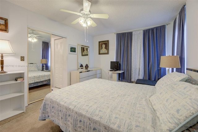 carpeted bedroom with a textured ceiling, ceiling fan, and a closet