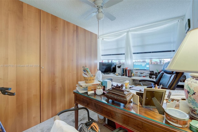 carpeted office space featuring ceiling fan and a textured ceiling