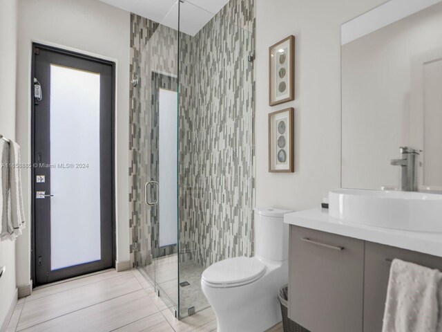 bathroom with vanity, tile walls, toilet, and a shower with door