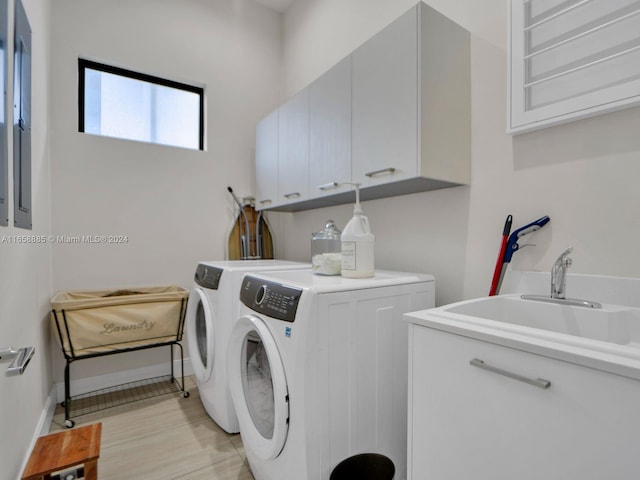 washroom with washing machine and dryer, sink, light hardwood / wood-style flooring, and cabinets