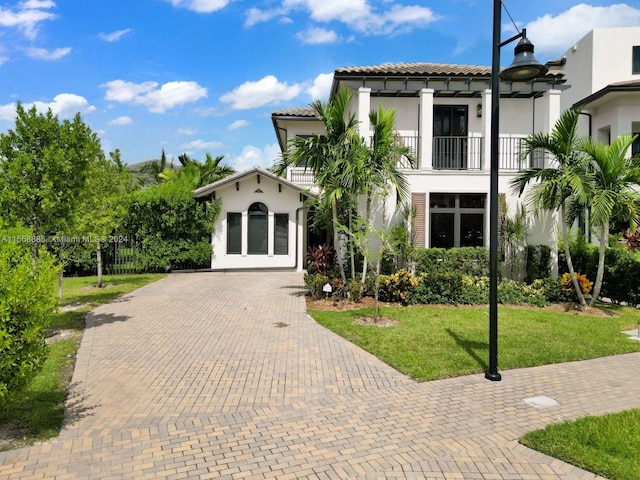 mediterranean / spanish home with a balcony and a front lawn