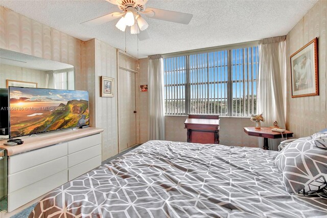 living room featuring ceiling fan, a wall of windows, carpet floors, and a textured ceiling