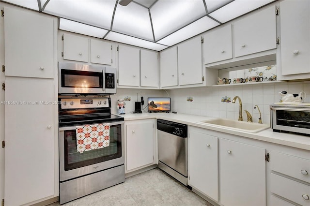 kitchen featuring backsplash, appliances with stainless steel finishes, light countertops, and a sink