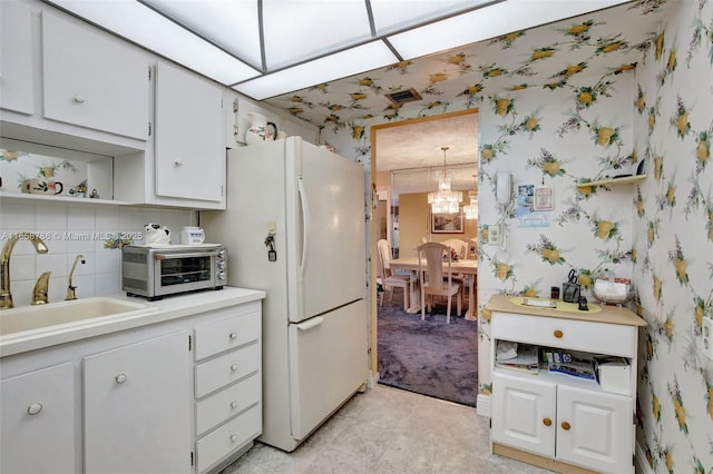 kitchen with wallpapered walls, a toaster, freestanding refrigerator, and a sink