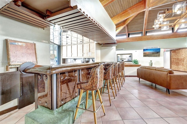 bar with tile patterned flooring, a community bar, wood ceiling, and vaulted ceiling with beams