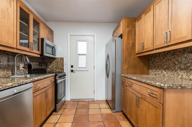 kitchen with sink, appliances with stainless steel finishes, dark stone counters, and decorative backsplash