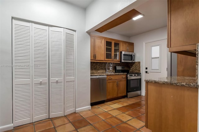 kitchen featuring appliances with stainless steel finishes, backsplash, light tile patterned floors, and stone counters