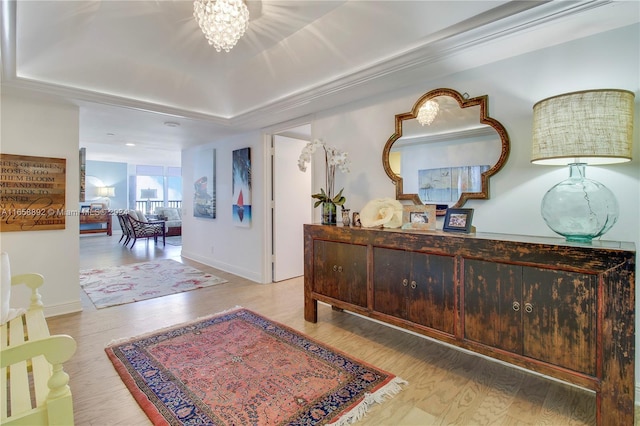 interior space with an inviting chandelier, a raised ceiling, and hardwood / wood-style floors