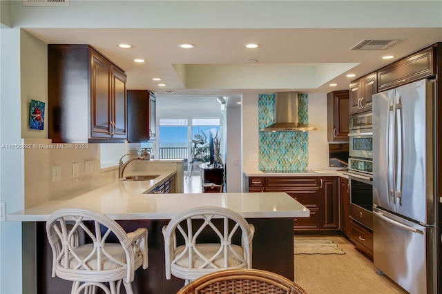 kitchen with stainless steel appliances and wall chimney exhaust hood