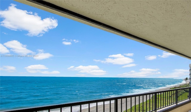 balcony featuring a water view and a beach view