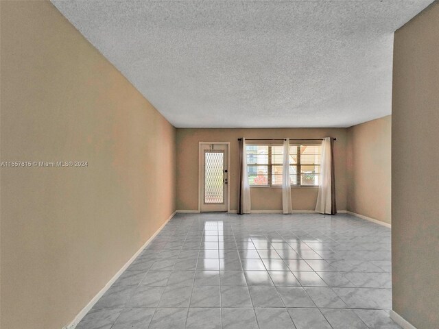 tiled spare room featuring a textured ceiling