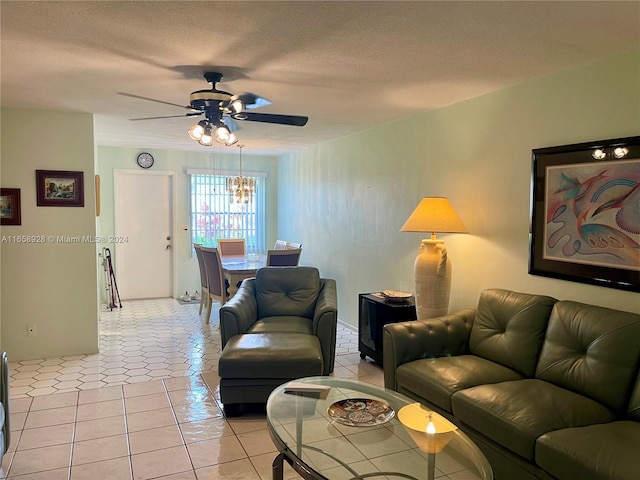 living room featuring ceiling fan with notable chandelier, a textured ceiling, and light tile patterned floors