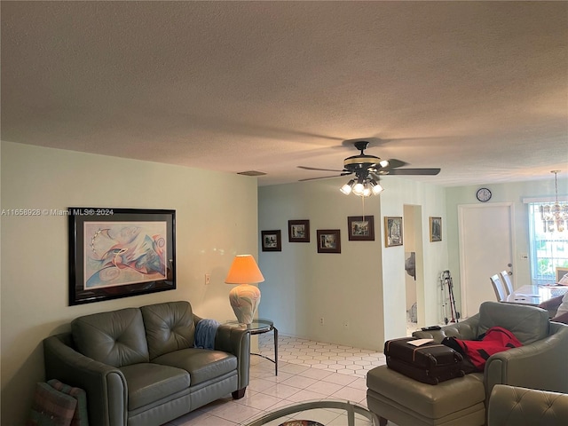 tiled living room with a textured ceiling and ceiling fan with notable chandelier