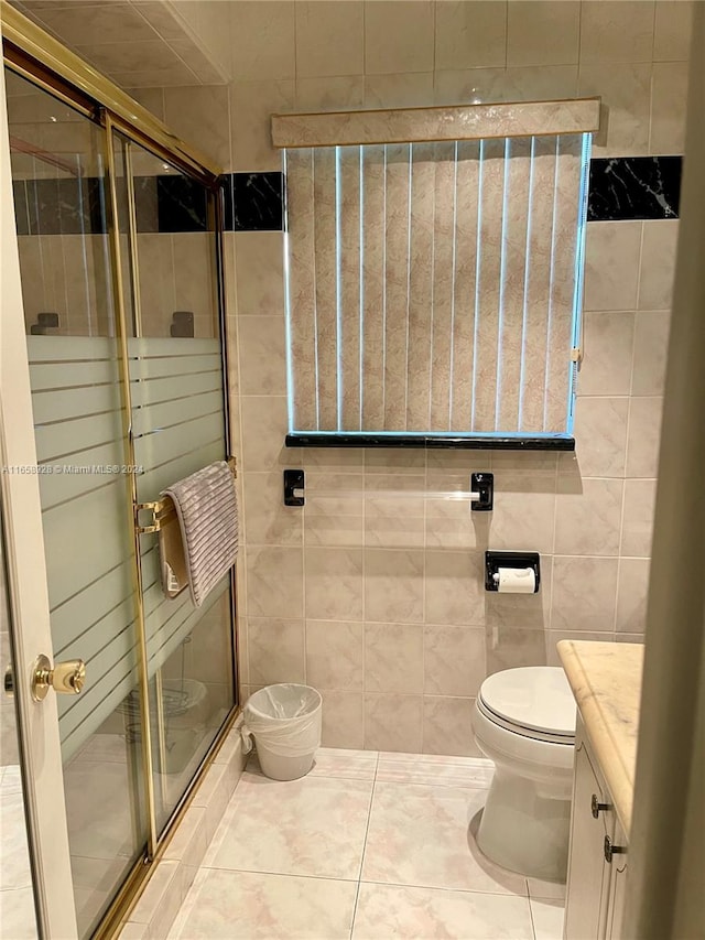 bathroom with tile patterned floors, toilet, tile walls, a shower with shower door, and vanity