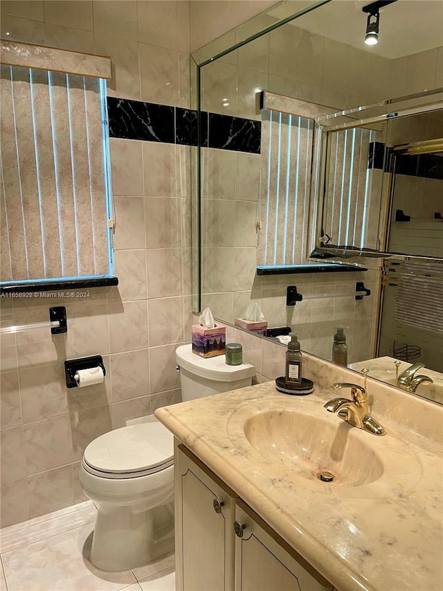 bathroom with vanity, toilet, tile walls, and a shower with shower door