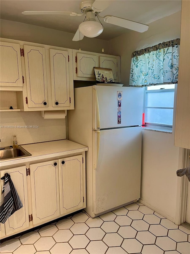 kitchen with white fridge, sink, white cabinetry, and ceiling fan