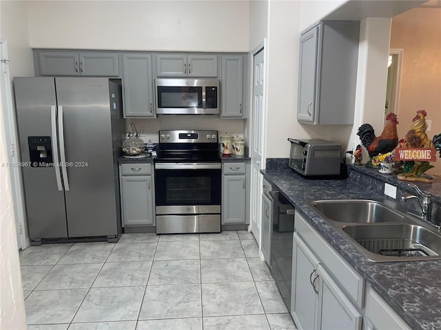 kitchen featuring gray cabinets, stainless steel appliances, light tile patterned flooring, and sink