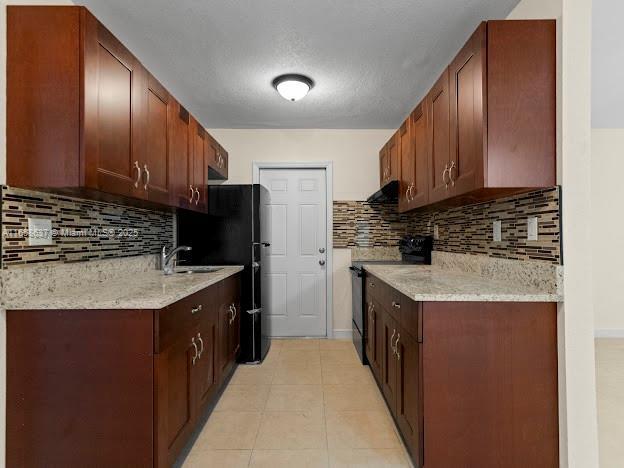 kitchen featuring light stone countertops, sink, tasteful backsplash, stainless steel range with electric cooktop, and exhaust hood