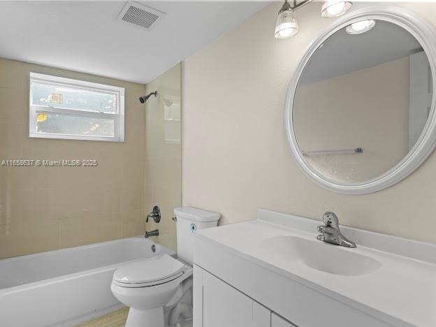 full bathroom featuring tiled shower / bath combo, toilet, and vanity