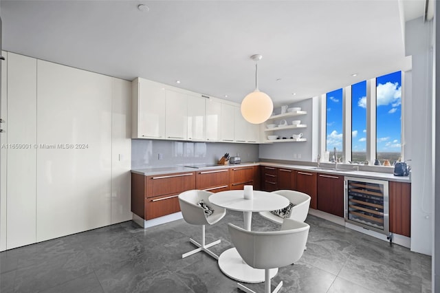 kitchen featuring pendant lighting, beverage cooler, backsplash, sink, and white cabinetry