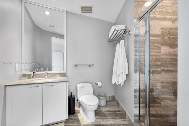 bathroom featuring toilet, walk in shower, hardwood / wood-style floors, vanity, and vaulted ceiling