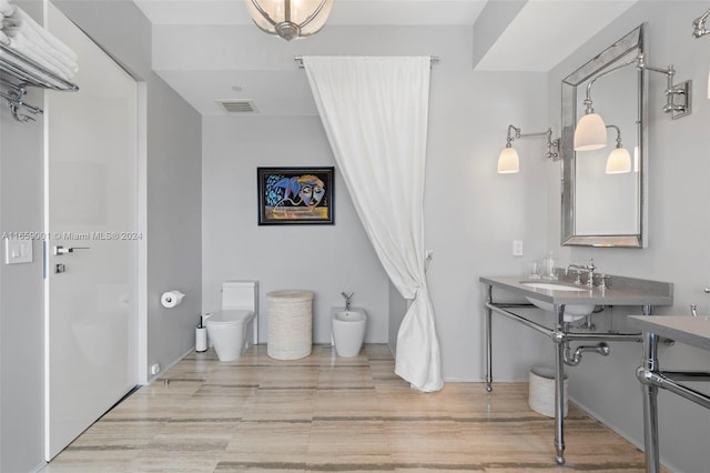 bathroom with toilet, hardwood / wood-style floors, and sink