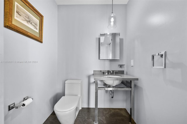 bathroom with toilet, sink, and tile patterned floors