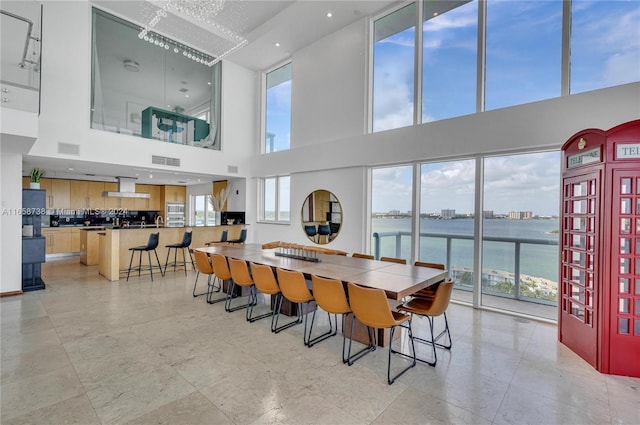 dining room featuring a water view, a wealth of natural light, and a towering ceiling