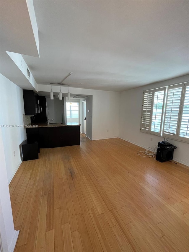 unfurnished living room with a wealth of natural light, light hardwood / wood-style flooring, rail lighting, and sink